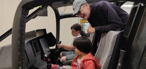 Joshua Kaewvichien (obscured in the background), undergraduate ambassador of the Vertical Flight Society's PSU Chapter and a junior majoring in aerospace engineering, shows children (and adults) the cockpit of a real XV-15, now converted into a simulator.